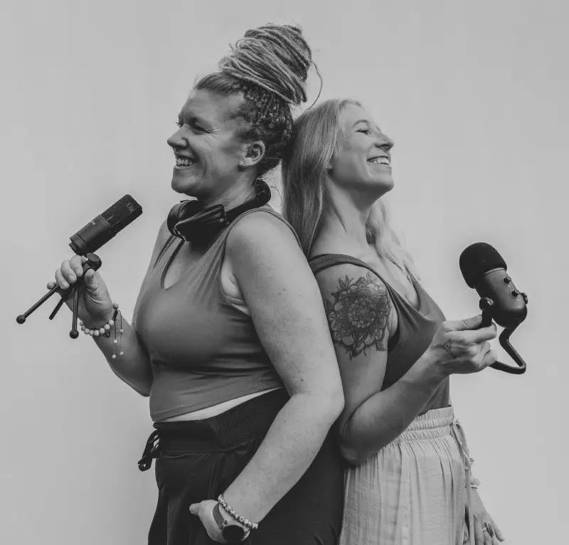Two women are holding microphones and smiling.