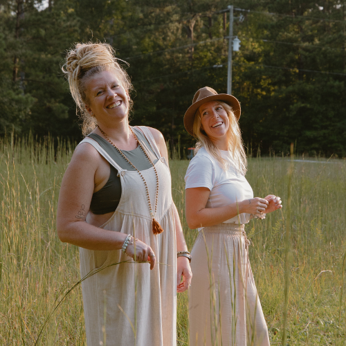 Two woman waling in the tall grass wearing white dress